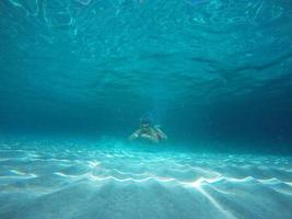 Beard man with glasses diving in a blue clean water photo