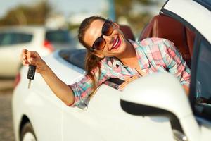 Young pretty woman sitting in a convertible car with the keys in hand photo