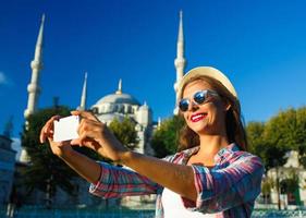 Girl making selfie by the smartphone on the background of the Blue Mosque, Istanbul. Turkey photo