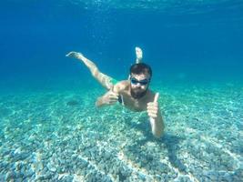 barba hombre con lentes buceo en un azul limpiar agua con pulgar arriba foto