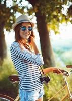 encantador joven mujer en un sombrero montando un bicicleta al aire libre. activo personas foto