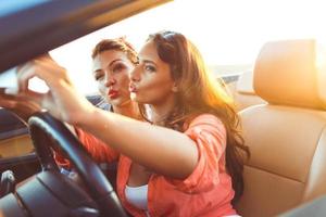 dos joven hermosa muchachas son haciendo selfie en un convertible foto