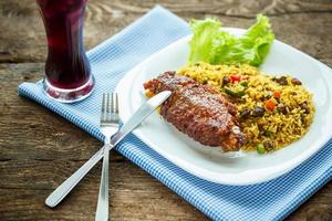 Tasty dishes from turkey meat with rice and salad leaves and a glass of juice with ice photo