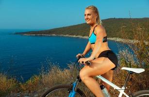 Woman cyclist on a mountain bike looking at the landscape of mountains and sea photo