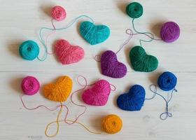 Multicolored Hearts with a balls of thread on white wooden background photo