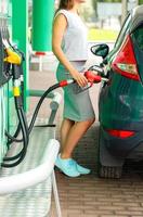 Woman fills petrol into the car at a gas station photo