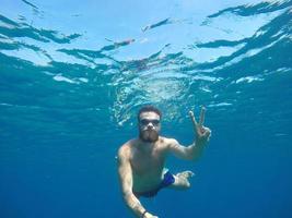 Young beard man with mask diving in a clean water photo