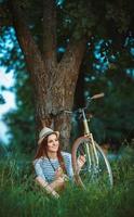 encantador joven mujer en un sombrero con un bicicleta al aire libre foto