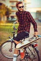 Stylish man in sunglasses riding a bike on city street photo