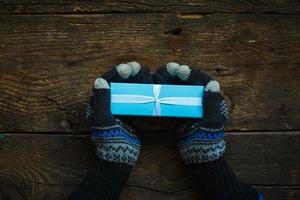 manos en guantes de invierno con caja de regalo de navidad foto