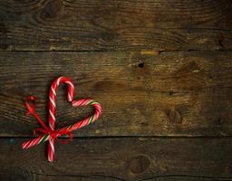 Candy canes in the heart shape on a wooden background photo