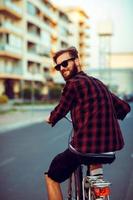 Young man in sunglasses riding a bike on city street photo