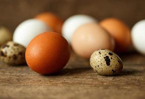 Chicken and quail eggs on a wooden rustic background photo
