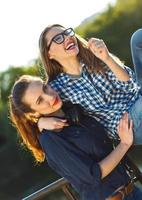 dos juguetón muchachas teniendo divertido al aire libre a puesta de sol ligero foto