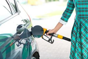 Woman fills petrol into her car at a gas station photo
