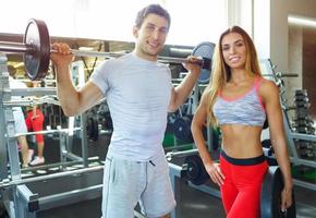 Athletic couple with barbell doing exercises in the gym photo