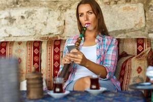 Woman smoking a hookah and uses smartphone in a cafe in Istanbul, Turkey photo