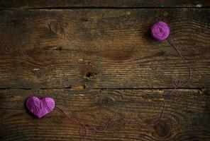 Purple Heart with a ball of thread on on old shabby wooden background photo