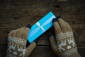 manos en guantes de invierno con caja de regalo de navidad foto