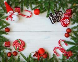 Navidad frontera con abeto árbol sucursales, Navidad decoraciones y caramelo caña en blanco de madera tableros foto