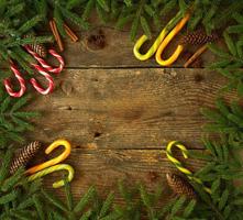 Christmas tree branch with cones, cinnamon, dittany and candy cane on wooden background with copyspace photo