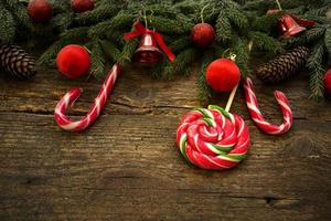 Christmas border with fir tree branches, cones, christmas decorations and candy cane on rustic wooden boards photo