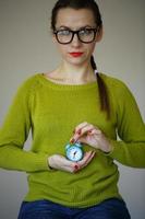 Little blue alarm clock in the hands of young woman photo