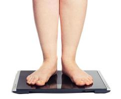 Bare female feet standing on bathroom scale photo