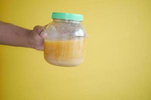 homemade ghee in container against yellow background photo