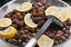 negro aceituna y limón en un cuenco en mesa foto