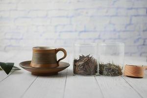 Dry tea leaves in a jar and tea cup on table photo