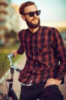 Man in sunglasses riding a bike on city street photo