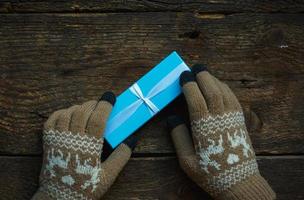 hembra manos en invierno guantes con Navidad regalo caja foto