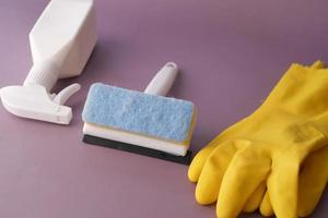 spray de limpieza de ventanas, cepillo y guantes sobre fondo morado foto