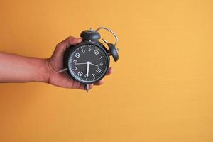 person hand holding alarm clock white background , photo