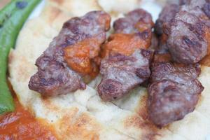 seekh kabab, pan naan y salsa en un plato foto