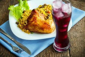 Tasty dish of chicken thigh with rice and lettuce and a glass of juice with ice photo