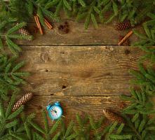 Navidad árbol rama con conos, canela, díctamo y azul alarma en de madera antecedentes foto