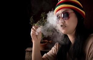 hermosa Asia mujer de fumar cigarrillos a canabis árbol antecedentes foto