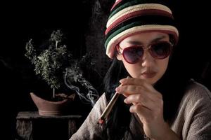 Beautiful Asia women smoking weed at cannabis tree background photo
