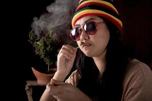 hermosa Asia mujer de fumar hierba a canabis árbol antecedentes foto