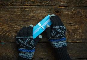 hembra manos en invierno guantes con Navidad regalo caja foto