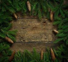 Christmas tree branches with cones on wooden texture ready for your design photo