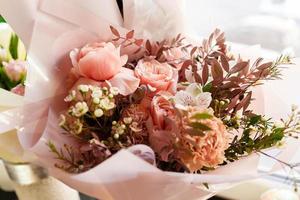 Beautifully packaged flower arrangement for celebrated mothers Day, birthday, anniversary, womans day in a festive paper package. The concept of a flower shop and flower delivery, florist work photo