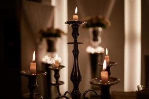 Burning candles on bronze candlestick against dark background at home.candles in the interior. Vintage style. Calm romantic atmosphere. Horizontal image for design. photo