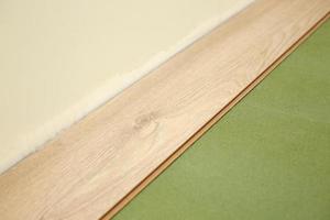 Installing wooden laminate or parquet floor in room over green base. assembling panels quickly and easily - affordable flooring. laying laminate flooring at home photo