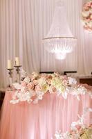 decoración festiva de la mesa de bodas con candelabros de cristal, candelabros dorados, velas y flores rosas blancas. día de la boda con estilo. foto