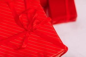 Red gift boxes with ribbons and Christmas baubles on white background. Surprises in boxes wrapped in red gift paper with bow. Concept of holidays and greeting cards. photo