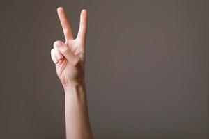 Woman hands isolated showing victory sign on grey background, gesture of victory. Policy position and belief. photo