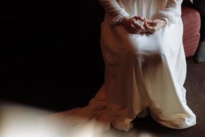 brides morning. Portraits of a bride in long white dress is sitting with folded arms. Woman is preparing for her wedding day photo